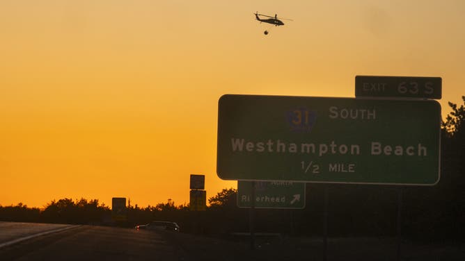 WESTHAMPTON, NEW YORK - MARCH 08: A rescue helicopter carries water along Route 27 on March 8, 2025 in Westhampton, New York. As strong winds fueled multiple brush fires on New York's Long Island, closing roads and reportedly burning structures. (Photo by Andrew Theodorakis/Getty Images)