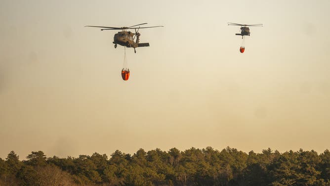 WESTHAMPTON, NEW YORK - MARCH 08: A rescue helicopter picks up water at Wild Wood Lake on March 8, 2025 in Westhampton, New York. As strong winds fueled multiple brush fires on New York's Long Island, closing roads and reportedly burning structures. (Photo by Andrew Theodorakis/Getty Images)