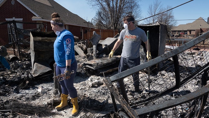 Jessi and Clark search through the ashes of their home for salvageable possessions after it was destroyed during Friday's wildfires on March 16, 2025 in Stillwater, Oklahoma.