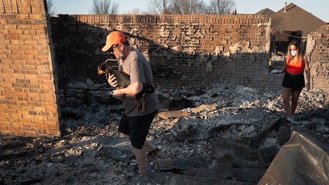 Steven Myers and his daughter Carmen visit their home after it was destroyed by Friday's wildfire on March 16, 2025 in Stillwater, Oklahoma.