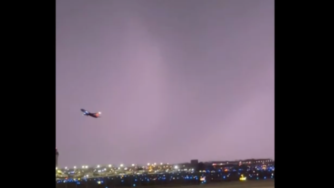 Plane can be seen taking off from St. Louis Airport as a tornado is illuminated by lightning in the background. 