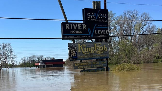 Flooding reaches the sign for River Road BBQ and other businesses on River Road in Louisville.