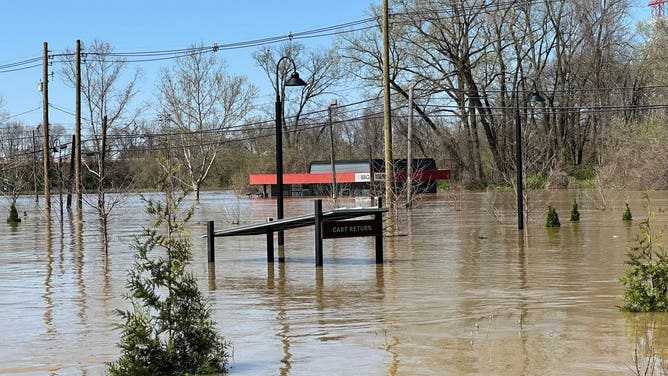 The flooded River Road BBQ sits in the background, with water nearly to its roof. 