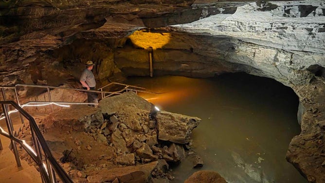 A ranger examines a water level gauge near the flooded River Hall cave passageway on Sunday, April 6, 2025.