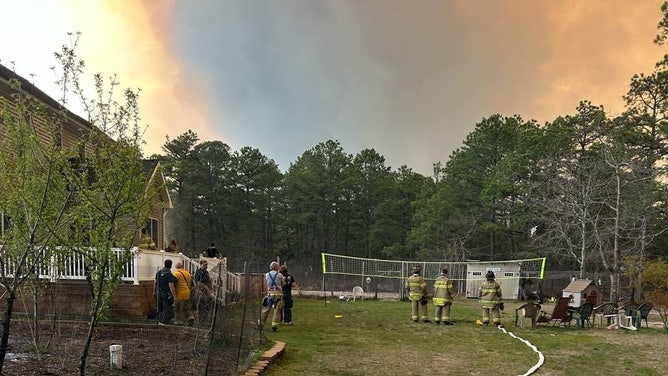Smoke from the Jones Road Fire in Ocean County, New Jersey, billows up to the sky behind a treeline on Tuesday.