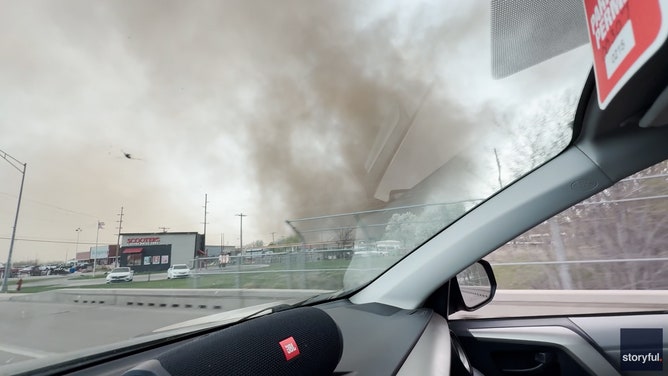 Video taken by Myles Nelson shows a column of swirling funnel cloud hover over buildings as a dust storm approaches in York, Nebraska, on Thursday.