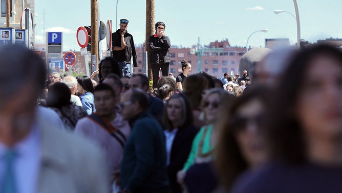 People wait outside the Atocha train station in Madrid after its closure as a massive power outage hits Spain on April 28, 2025.