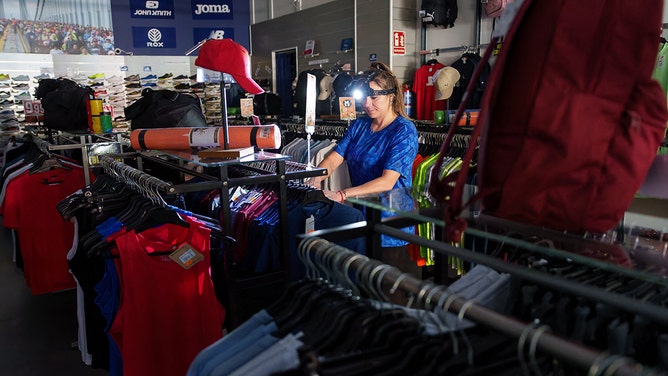 A saleswoman at a sports store works with a light on her head in Burgos on April 28, 2025, during a massive power cut affecting the entire Iberian peninsula and the south of France.