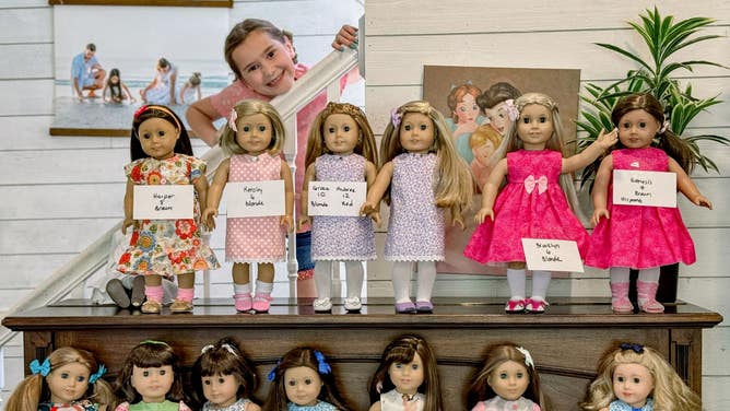 Kayleigh stands behind two rows of Appalachian Dolls. Each doll has a piece of paper indicating the name, age and hair color of the girl she will be given to.