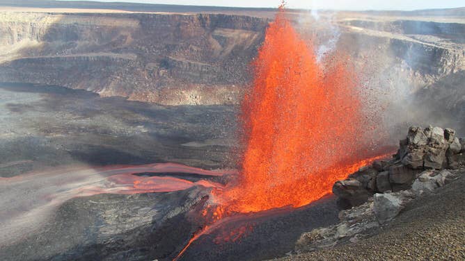 USGS scientists observe the western rim of Halemaʻumaʻu crater during an eruption.