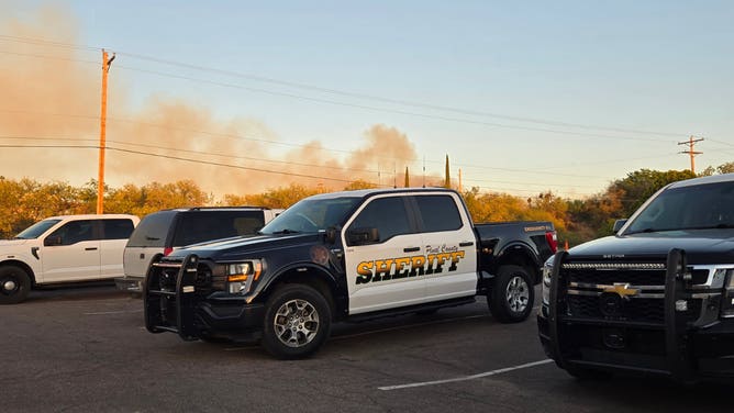Smoke from the Cody Fire looms behind a Pinal County Sheriff's Office vehicle.