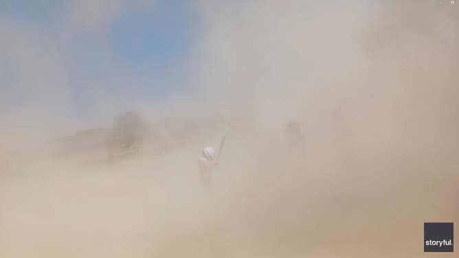 Dust devil shrouds Little League softball players in Illinois.
