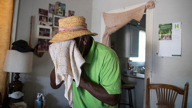 Feast Bennemie, 77, wipes sweat from his face while standing in the living room of his 5th Ward home Wednesday, June 16, 2021 in Houston.