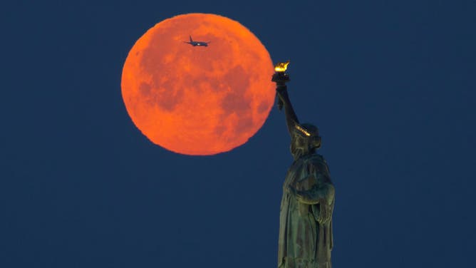 Full Strawberry Moon Sets Behind the Statue of Liberty in New York City