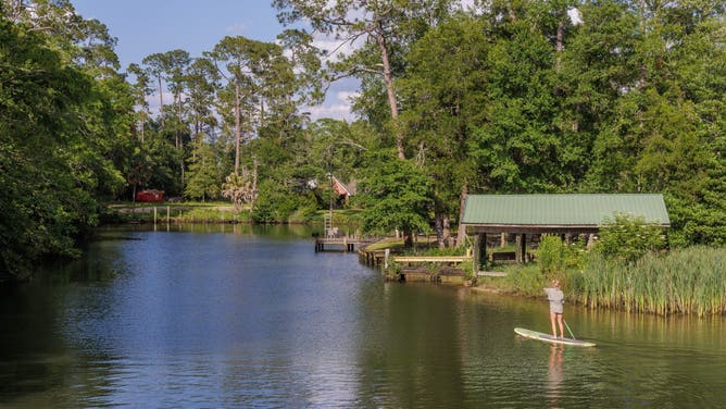 Young woman paddleboarding on the Magnolia River in Magnolia Springs, Alabama.