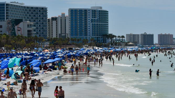 Tourists bustle along Clearwater Beach in Florida on this hot Saturday.