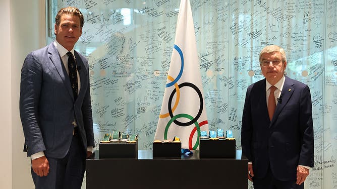 US swimmer Gary Hall Jr. (L) stands next to IOC president Thomas Bach (R) during a handover ceremony of the replicas of his Atlanta 1996 Olympic medals after the originals were destroyed with his house in the Los Angeles wildfires earlier this year, at the Olympic House in Lausanne on May 5, 2025.
