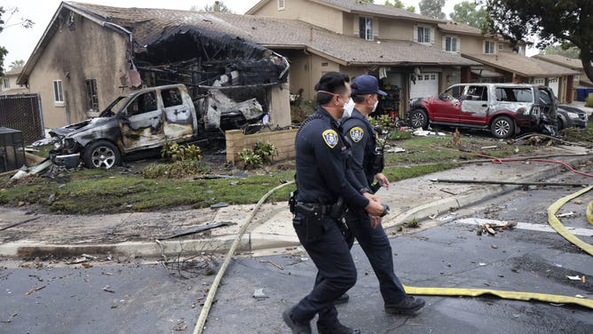 Police officers search the site where a small plane crashed on a San Diego, California, residential street on May 22, 2025.