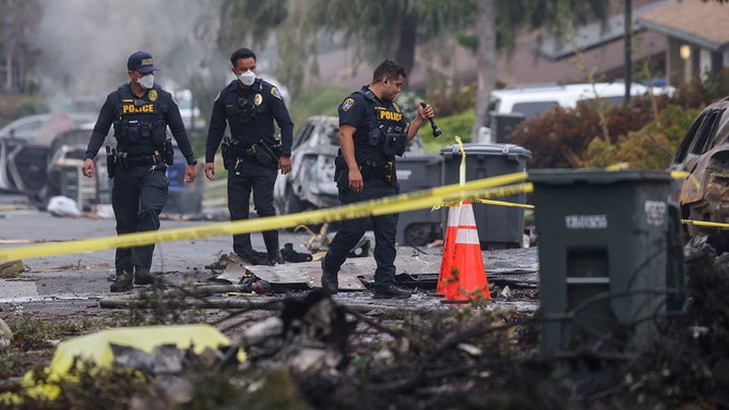 Investigators look through the site where a small plane crashed into a San Diego, California, residential street on May 22, 2025.