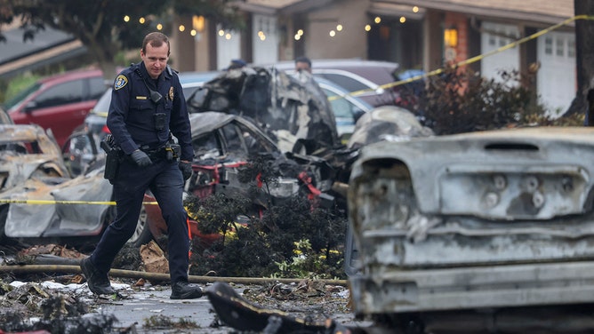 Investigators look through the site where a small plane crashed into a San Diego, California, residential street on May 22, 2025.