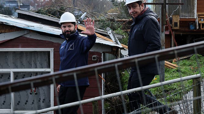 Chile's President Gabriel Boric greets a woman as he visits the affected area after the passage of a tornado in the city of Puerto Varas, Region de los Lagos, southern Chile, on May 26, 2025.