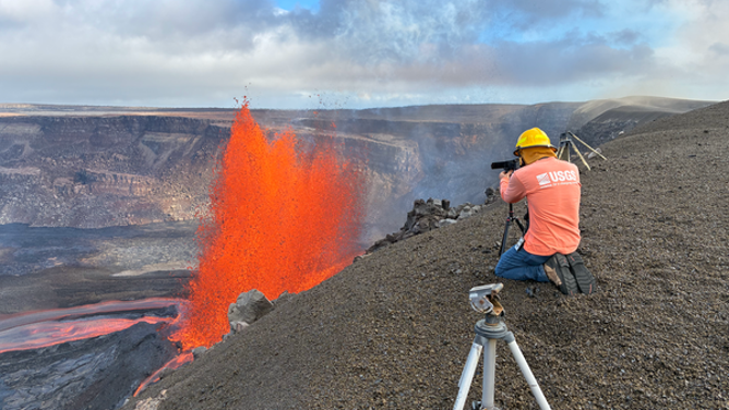 A USGS Hawaiian Volcano Observatory scientist observes a volcano erupting.