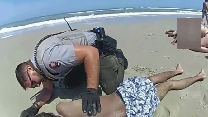 Officer carries teen from the water.