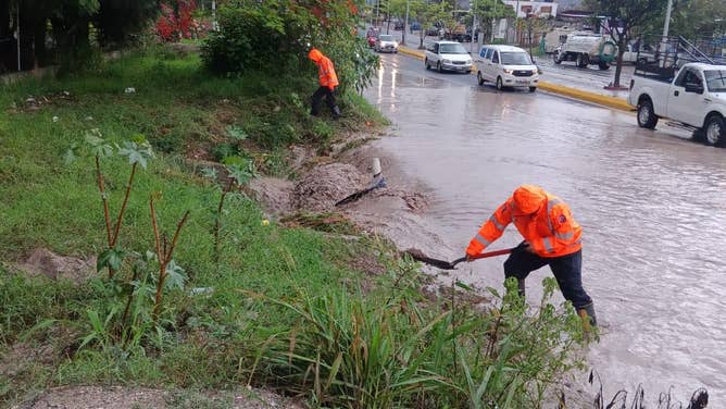Workers in Acapulco try and clear mud and debris amid flooding produced by Tropical Storm Dalila.