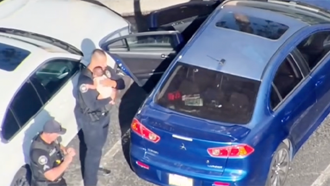 This image shows a police officer comforting a baby after it was rescued from a locked car on June 17, 2025.