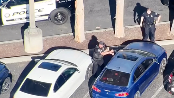 This image shows a police officer breaking a car window to rescue a baby locked inside on June 17, 2025.