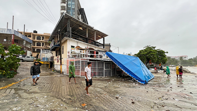 Residents walk past damages caused by Hurricane Erick in Bahia Principal, Puerto Escondido, Oaxaca on June 19, 2025. Erick, a category 4 hurricane on a scale of 5, made landfall in the Mexican state of Oaxaca (west) on the Pacific coast, the United States National Hurricane Center (NHC) reported. (Photo by CARLO ECHEGOYEN / AFP) (Photo by CARLO ECHEGOYEN/AFP via Getty Images)