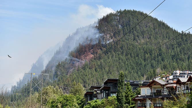 This photograph shows wildfires burning in the hills north of Tantalus Road, in Squamish, British Columbia on June 11, 2025.