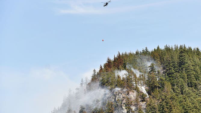A helicopter battles wildfires in the hills north of Tantalus Road, in Squamish, British Columbia on June 11, 2025.