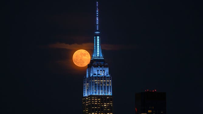 The full Strawberry Moon rises behind the Empire State Building in New York City on June 10, 2025, as seen from Weehawken, New Jersey.