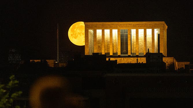 The full Strawberry Moon sets behind Anıtkabir, the mausoleum of Mustafa Kemal Ataturk, founder of modern Turkey, in Ankara, Turkey.