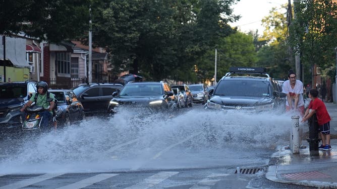 NEW YORK CITY, UNITED STATES - JUNE 24: Some residents in Queens open a fire hydrant to spray cool water on their streets during extreme heat as the temperatures hit 99 degrees in Manhattan, while Kennedy Airport hit 102 degrees on Tuesday afternoon, surpassing the high of 96 degrees set on June 24, 1888, in New York City, United States June 24, 2025. (Photo by Selcuk Acar/Anadolu via Getty Images)