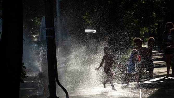 CHICAGO, ILLINOIS - JUNE 23: Kids play in an open fire hydrant as temperatures climbed into the mid-90s on June 23, 2025 in Chicago, Illinois. Today marked the third straight day the city was under an extreme heat warning. (Photo by Scott Olson/Getty Images)