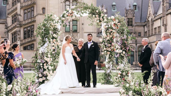 Jansen and Travis hold hands at their wedding ceremony.