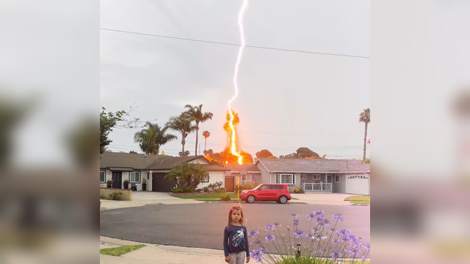 Lightning strikes behind child in Huntington Beach. CA.