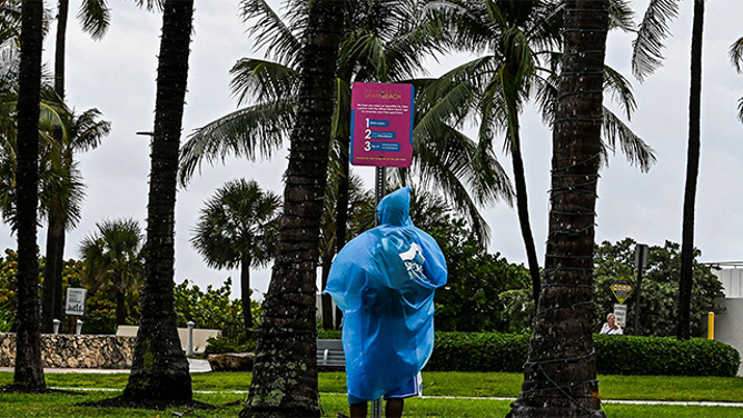 FILE - People wear rain covers as they walk in the park during heavy rain in Miami Beach, Florida, on April 12, 2023.