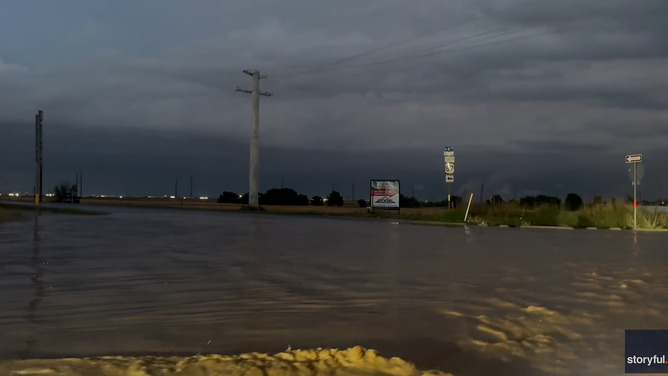 Cars drive through flooded streets in Lubbock Thursday night.