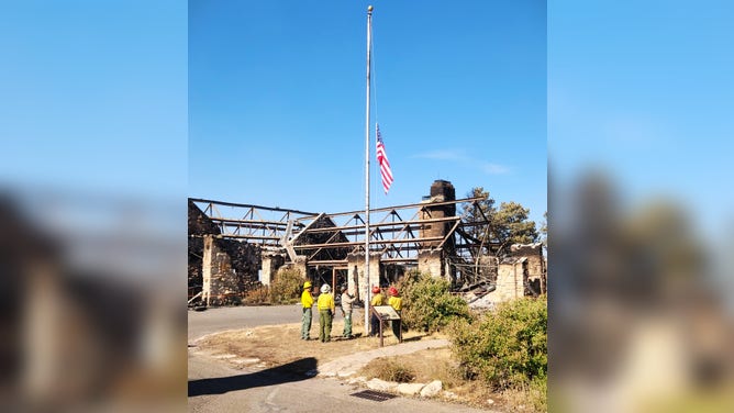 Amid the ashes of the Grand Canyon Lodge, firefighters from the Complex Incident Management Team paused to raise the American flag.