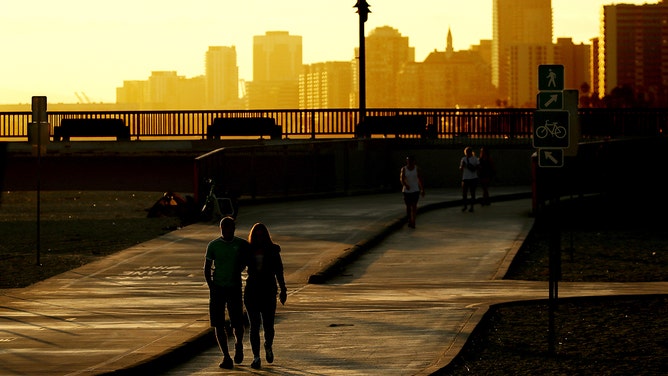 Beachgoers walk along the shore near the Belmont Pier in Long Beach on the first day of fall.