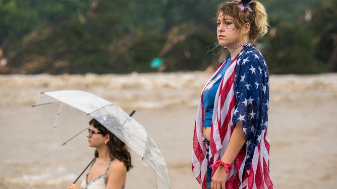 Laeighton Sterling (R) and Nicole Whelam observe flood waters from the banks of the Guadalupe River on July 4, 2025 in Kerrville, Texas.