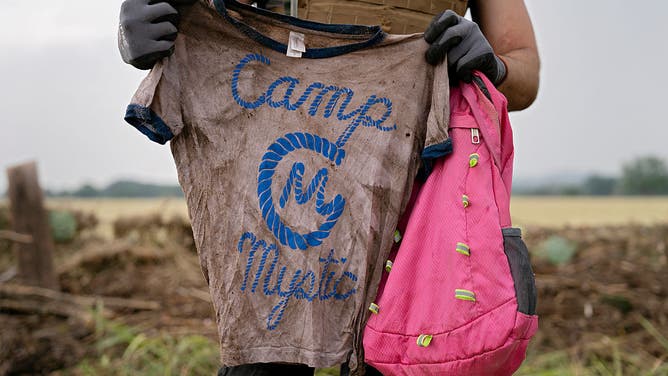 A search and rescue volunteer holds a T-shirt and backpack with the words Camp Mystic on them in Comfort, Texas on July 6, 2025.