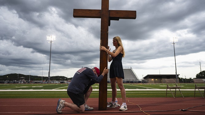Attendees hold a cross during a vigil at a high school stadium in Kerrville, Texas, US, on Wednesday, July 9, 2025. Crews in central Texas are digging through massive piles of debris, overturned vehicles and shattered homes for a sixth day as the search continues for victims of flash floods that killed more than 100 people over the Fourth of July weekend.