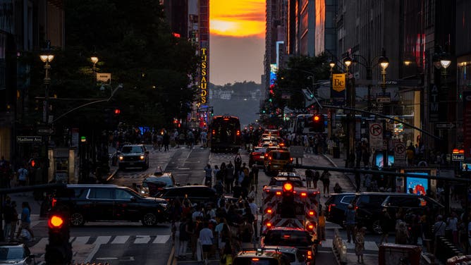 NEW YORK, NY - JULY 11: Crowds flock to 42nd Street in Manhattan to witness the second Manhattanhenge of the year on July 11, 2025. Manhattanhenge is a biannual event when the setting sun aligns precisely with the east-west grid of Manhattan's streets, creating a rare and picturesque urban sunset.