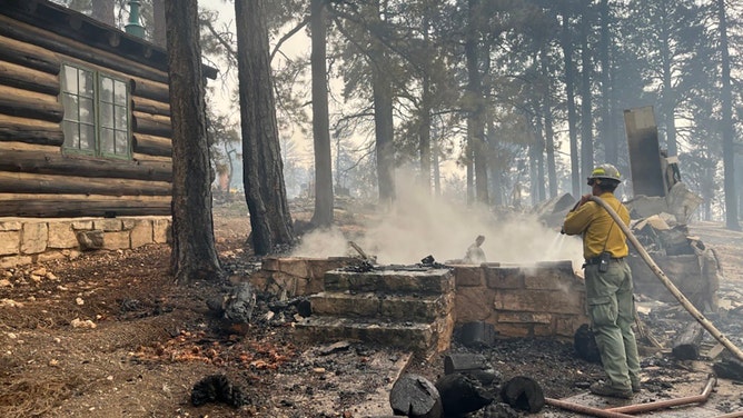 In this handout image provided by Grand Canyon National Park, A firefighter stands near smoldering debris and active flames amid the charred remains of burned structures near the Grand Canyon Lodge at Grand Canyon National Park on July 13, 2025.
