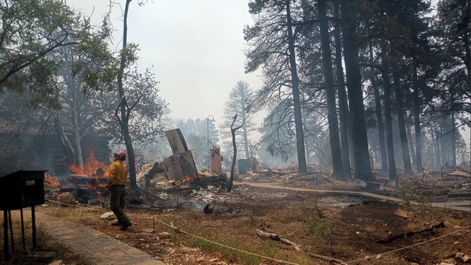 In this handout image provided by Grand Canyon National Park, A firefighter stands near smoldering debris and active flames amid the charred remains of burned structures near the Grand Canyon Lodge at Grand Canyon National Park on July 13, 2025.
