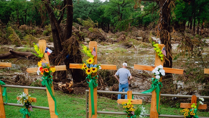 Mike Sowers, 80, looks at debris near crosses lined along the Guadalupe River at Guadalupe Park in Kerrville, Texas on Sunday, July 13, 2025.